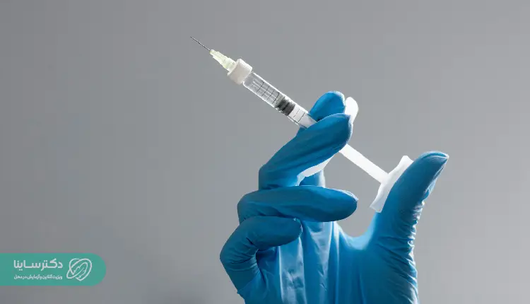 A gloved hand holding a medical syringe against a neutral background, representing preparation for blood sampling procedures such as the MCH test
