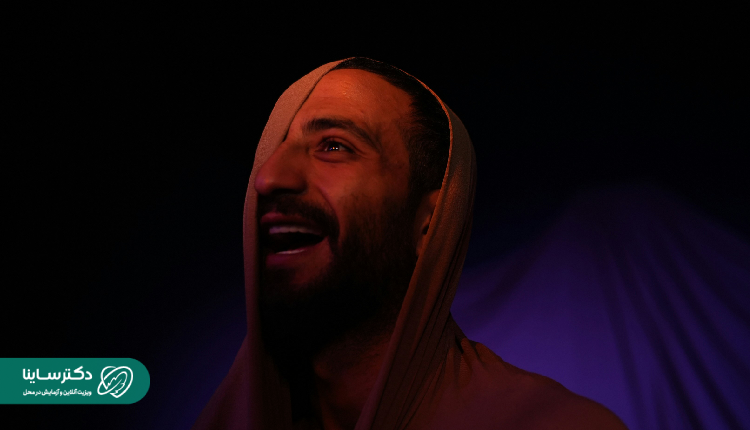 Alt text: Histrionic personality - A man under dramatic lighting with a wide smile and wrapped in fabric, reflecting theatrical and emotionally charged presentation.