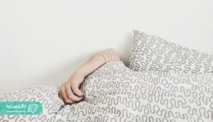 An arm partially covered by patterned bed sheets, suggesting sleep interruption or unusual sleep posture often associated with Sleep paralysis treatment.